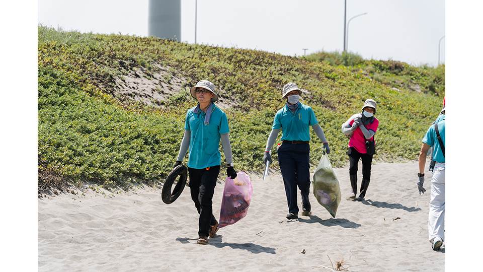 即使頂著烈日，參與淨灘的民眾仍辛勤地清理沙灘上的廢棄物。
